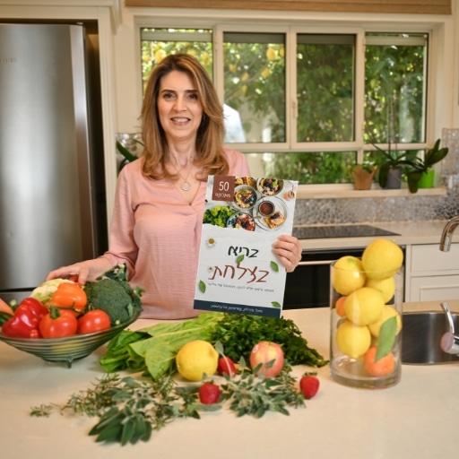 מיכל פדרליין מחזיקה את חוברת המתכונים הדיגיטלית בריא בצלחת